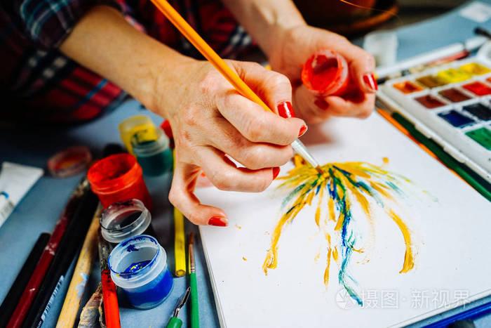 妇女艺术家油漆用刷子和明亮的水彩颜料在白色纸照片-正版商用图片03h